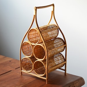 May include: A natural woven wicker wine rack with a handle. The rack has five compartments for storing wine bottles.