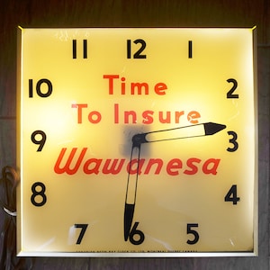 May include: A yellow clock face with black numbers and a black hand pointing to the number 3. The clock face has the text "Time To Insure Wawanesa" in red letters.