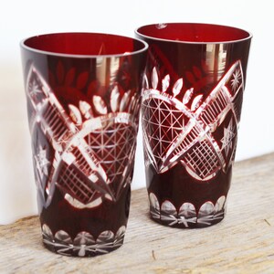 Könnte beinhalten: Zwei rote Glasbecher mit einem geschliffenen Glasdesign. Die Gläser haben ein klares, filigranes Muster.