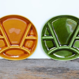 May include: Two ceramic fondue plates, one orange and one green, with five sections each. The plates are designed for serving fondue with dipping items.