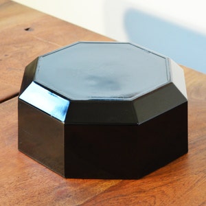 Pode incluir: Uma caixa octogonal preta com um acabamento liso e brilhante. A caixa &eacute; feita de um material duro e dur&aacute;vel e tem um design simples e elegante.