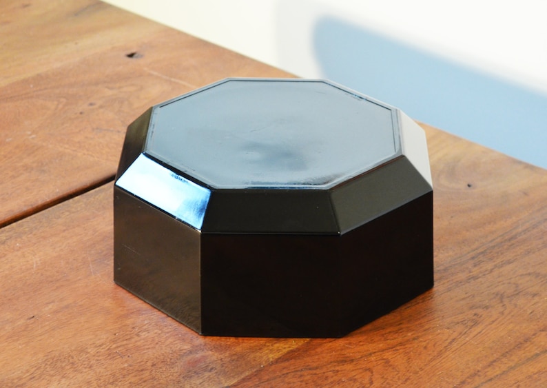 Pode incluir: Uma caixa octogonal preta com um acabamento liso e brilhante. A caixa &eacute; feita de um material duro e dur&aacute;vel e tem um design simples e elegante.