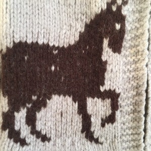 May include: A knitted cardigan with a brown unicorn design. The cardigan is made of a soft, fluffy yarn.