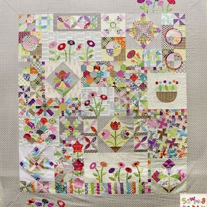 Puede incluir: Un edredón de patchwork con una variedad de patrones florales y geométricos. El edredón presenta cuadrados con flores aplicadas, molinetes y otros diseños en una mezcla de colores. El borde es un pequeño patrón de cuadros. El edredón tiene el texto "Sewma Party" en la esquina inferior derecha.