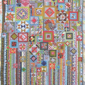 May include: A colourful quilt featuring a variety of patterns and colours, including red, blue, green, and yellow. The quilt is made up of squares and rectangles, and it has a patchwork design.