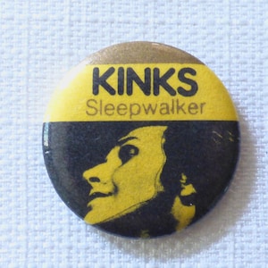 May include: A yellow and black button with the text "KINKS Sleepwalker" on it. The button features a black and white image of a person's face.