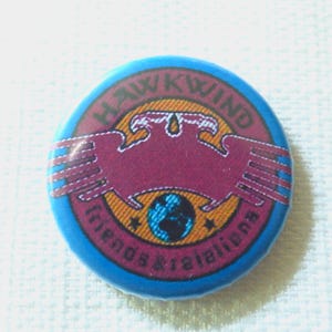 May include: A blue and orange round button with the text "Hawkwind Friends & Relations" and a graphic of a bird with a globe in the center.