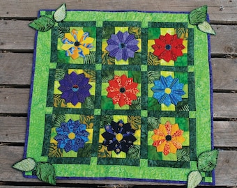 Flores coloridas que se destacan sobre un campo verde brillante, patchwork, acolchado y aplicado