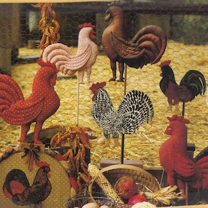 May include: A collection of handcrafted rooster decorations in various colors and patterns. The roosters are made of fabric and wood, with details like polka dots and black and white patterns. Some are mounted on sticks, others are part of a decorative display.