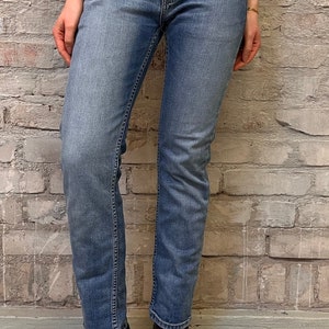 Könnte beinhalten: Eine hellblaue Jeans mit geradem Bein. Die Jeans hat einen klassischen Fünftaschen-Stil und einen Knopfverschluss.
