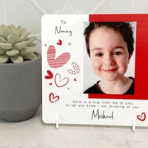 May include: A white card with red hearts and a photo of a child. The card says "To Nanny" and "Here is a hug from me to you, to let you know I am thinking of you. Michael."