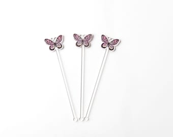 May include: Three silver butterfly cocktail stirrers with pink and black butterfly designs.
