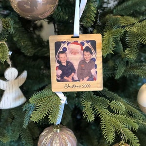 May include: A wooden Christmas ornament with a photo of two children with Santa Claus. The ornament is decorated with the text "Christmas 2009".