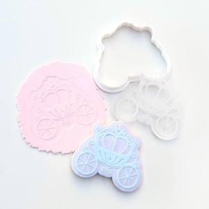 May include: A selection of crafting items, including a carriage-shaped cookie cutter, a carriage imprint in pink clay, and a carriage-shaped cookie in light blue and purple. The items are on a white surface.