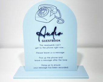 May include: A light blue sign with a black outline of a rotary phone and the text "Audio Guestbook". The sign has instructions for leaving a message for the newlyweds.