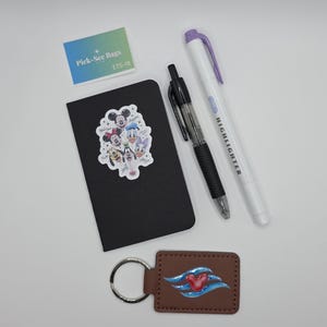 May include: A black notebook with a Disney character sticker, a black retractable pen, a white highlighter with a purple cap, a brown rectangular keychain with a red Mickey icon and blue waves, and a small card labeled Pick-See Bags ETS-18.