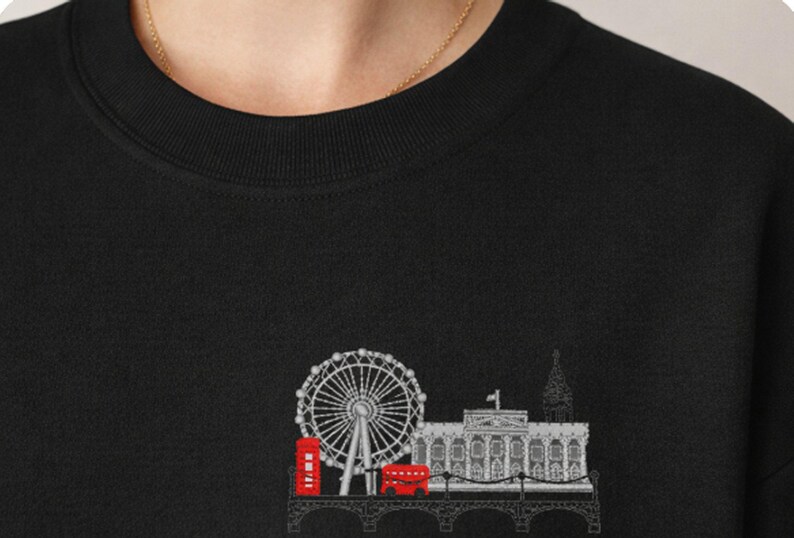 May include: Black sweatshirt featuring an embroidered London skyline design. The design includes the London Eye, a red telephone booth, a double-decker bus, and other iconic landmarks. The sweatshirt has a crew neck and long sleeves.
