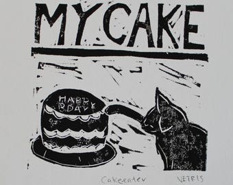 May include: Black and white linocut print featuring the text "MY CAKE" above a cake with "HAPPY BDAY" on top. A cat reaches for the cake. The print is signed "VETRIS" and labeled "Cakeeater".