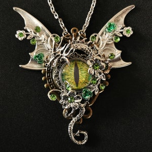 May include: A silver dragon pendant necklace with a green eye, silver wings, and green floral accents.