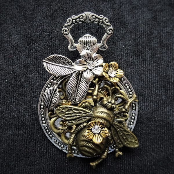 Charming Steampunk pocket watch-style Queen Bee pin brooch featuring bronze bee charm and silver and gold flowers & foliage