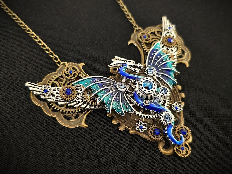 May include: A steampunk-style necklace featuring a blue and green dragon with intricate metal gears and blue crystals.