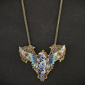 May include: A gold necklace with a blue and silver dragon pendant. The dragon has intricate details and is adorned with rhinestones.