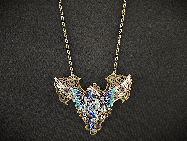 May include: A gold necklace with a blue and silver dragon pendant. The dragon has intricate details and is adorned with rhinestones.