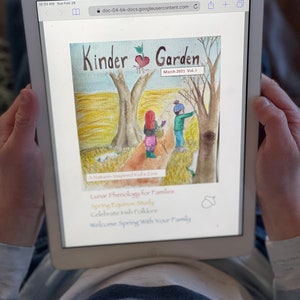 May include: A digital magazine cover titled "Kinder Garden" with a watercolor illustration of two children in a forest. The magazine is a nature-inspired kids zine with articles on lunar phenology, spring equinox study, Irish folklore, and welcoming spring with your family.