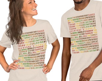May include: Two people wearing beige t-shirts with a Thanksgiving-themed text design. The text includes phrases like "Pass the cranberry sauce" and "Thank you for loving me" in a vertical layout, using various colors.