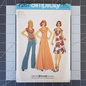 May include: A vintage sewing pattern for a dress and a top. The pattern is from Simplicity and the number is 7267. The pattern is for stretch knits only. The pattern shows three women wearing the garments. The woman on the left is wearing a blue top and pants. The woman in the middle is wearing a long, peach-colored dress. The woman on the right is wearing a short, floral dress.