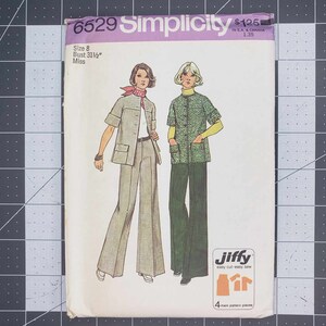 Könnte beinhalten: Simplicity Schnittmuster Nummer 6629 für ein Jiffy Oberteil und eine Hose, die einfach zu schneiden und zu nähen sind. Das Schnittmuster ist für Größe 8, Brustumfang 31 1/2 Zoll, und ist für Damen. Das Schnittmuster zeigt zwei Modelle, die das Oberteil und die Hose tragen. Ein Modell trägt ein grünes Oberteil und eine grüne Hose, und das andere Modell trägt ein braunes Oberteil und eine braune Hose.