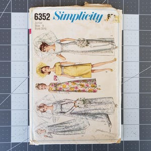 Puede incluir: Patrón de costura Simplicity número 6352 para un vestido junior talla 9 con un contorno de pecho de 77,5 cm. El patrón muestra cuatro estilos diferentes de vestidos, todos con fondo blanco y con diferentes patrones florales.