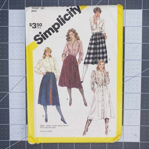 May include: A Simplicity sewing pattern envelope for a miss waist 25 inch size. The front features illustrations of four different skirt styles, including a blue skirt, a maroon skirt, a black and white plaid skirt, and a white button-front skirt.