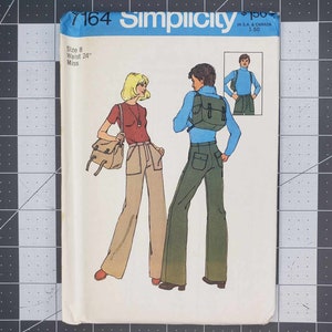 May include: A sewing pattern for a pair of pants, with a size 8, 24" waist, miss. The pattern shows two people wearing the pants, one in a blue shirt and the other in a red shirt. The pattern is from Simplicity, number 7164.