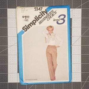 May include: A Simplicity sewing pattern for a pair of pants, size 8, waist 24 inches. The pattern is labeled "Beginner's Choice" and "Level 3". The pattern features a woman wearing the pants with a white shirt and a brown sweater.