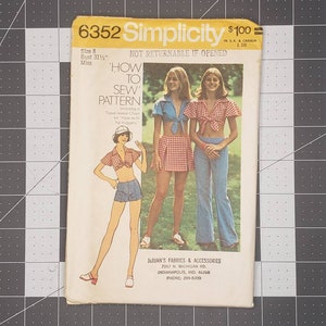 Puede incluir: Patrón de costura vintage Simplicity número 6352 para un patrón de "Cómo coser". El patrón es para una talla 8, busto 31 1/4 pulgadas, y es para mujeres. El patrón no es reembolsable si se abre. El patrón presenta tres modelos que llevan diferentes versiones del patrón, que incluye un top corto con un nudo en la parte delantera. Una modelo lleva una falda de cuadros rojos y blancos, otra lleva pantalones vaqueros azules y la tercera lleva pantalones cortos de mezclilla. El patrón está impreso en un fondo blanco con texto amarillo y negro.
