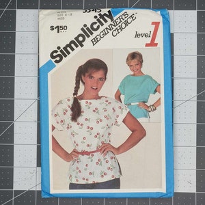 May include: A Simplicity Beginner's Choice sewing pattern envelope, number 5545, featuring a white top with a red cherry print and short sleeves. The envelope displays two photographs of the garment, text including 'Petite Size 6-8 Miss', and a blue border.