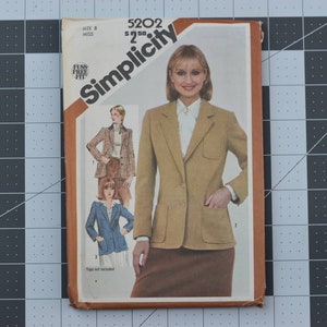 May include: Simplicity sewing pattern number 5202 for a blazer. The pattern is for size 8 miss and includes a fuss-free fit. The pattern shows a woman wearing a brown blazer with a white shirt and a brown skirt.