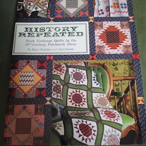 May include: A book cover titled "HISTORY REPEATED" featuring a collage of colorful quilt squares. The cover includes the text "Block Exchange Quilts by the 19th-Century Patchwork Divas" and the authors' names. The quilts showcase various patterns and colors.