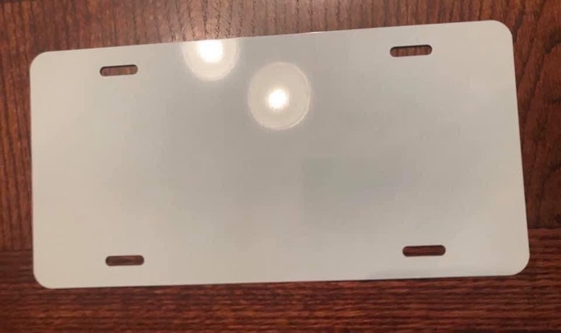 May include: A blank white metal license plate with four holes for mounting.
