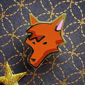 May include: A red fox pin with a black outline and pink ears. The fox is looking to the right and has a slightly angry expression.