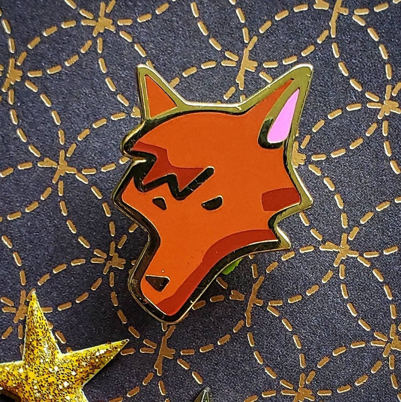 May include: A red fox pin with a black outline and pink ears. The fox is looking to the right and has a slightly angry expression.