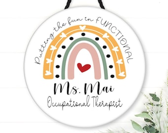 May include: A round sign with a rainbow design and the text "Putting the fun in functional" and "Ms. Mai Occupational Therapist".