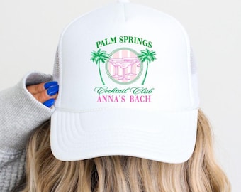 May include: White trucker hat with a green and pink logo that says "Palm Springs Cocktail Club Anna's Bach".