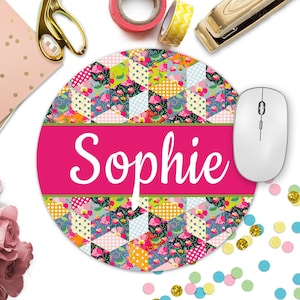 May include: A round pink and green mouse pad with a colorful patchwork design and the name "Sophie" in white text. The mouse pad is on a white surface with confetti.