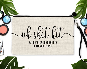 Peut inclure: Une trousse de maquillage en toile beige avec une fermeture éclair et une dragonne noires. Le sac porte l'inscription "oh shit kit" en cursive, ainsi que "PAIGE'S BACHELORETTE CHICAGO 2021". Du maquillage et des feuilles tropicales entourent le sac.