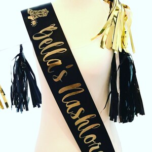 Puede incluir: Sash de sat&eacute;n negro con letras doradas que dicen "Bella's Bachelorette" y una bota dorada con purpurina y una espuela.