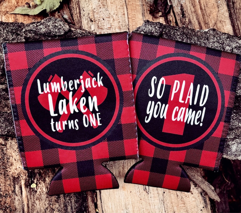 May include: Two red and black plaid beverage insulators with a white circle on each. The left insulator says "Lumberjack Laken turns one". The right insulator says "So plaid you came!"