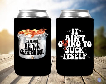 May include: Black can cooler featuring a watercolor illustration of a crawfish boil with the text "4th Annual Melton Crawfish Boil." The reverse side displays the phrase "It Ain't Going to Suck Itself" with a crawfish graphic.