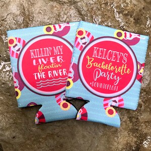 May include: Two blue and red can coolers with a summer theme. One cooler says "Killin' my liver, floatin' the river" and the other says "Kelcey's Bachelorette Party #DownToFloat"